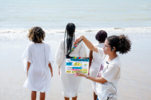 Mulheres à beira do mar, uma segura a claquete de História de Preta