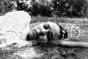 Mulher olha para a câmera com parte do rosto submersa em água